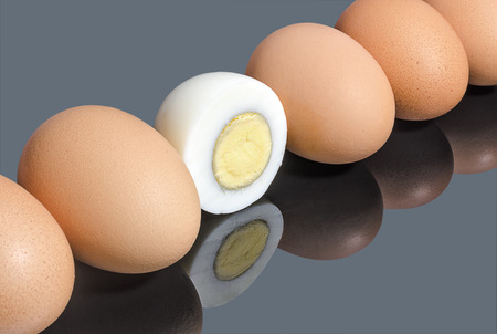 Half boiled chicken egg in a row of whole eggs