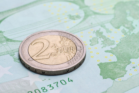 Coin two euros  on the banknote of one hundred euro