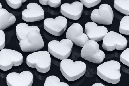 Pills in the form of white hearts on a dark background. Healthcare and medicine