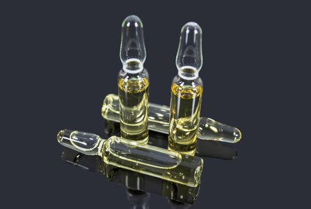 Ampoules with yellow medicine for injection on dark mirror surface. medicines and healthcare