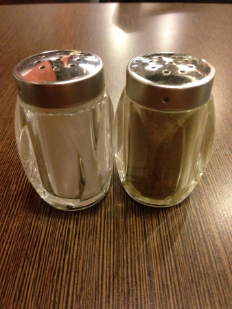 Salt and pepper shaker on wooden tableの素材