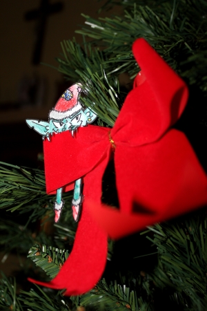 Green Evil elf with christmas hat hiding behind a red ribbon on a Christmas treeの写真素材