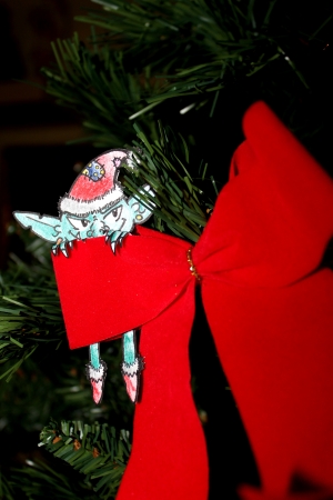 Green Evil elf with christmas hat hiding behind a red ribbonの写真素材