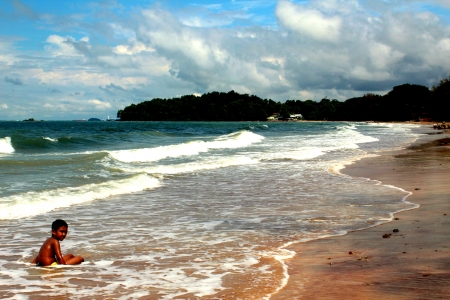 Little boy sitting at the shore while enjoying the waves in Port Dicksonのeditorial素材