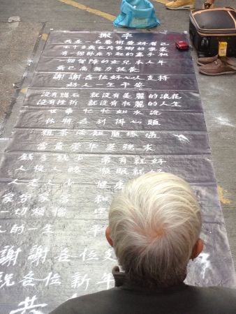 Old Asian man writing using sand begging for money along Tung Choi Street, Hong Kongの素材