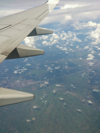 Airplanes wing flying high above thecityの素材