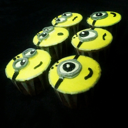 A set of minions cupcakes in pitch black background with different expressionsの素材