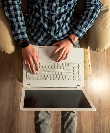 Handsome young man using laptop computer at home. Student men resting in his room. Online shopping, home work, freelance, online learning, studying concept. Distance educationの写真素材