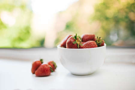 sweet strawberries in a saucer on a summer windowの写真素材
