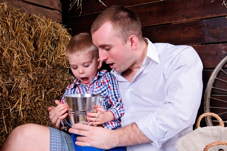 father and son, in a shed on straw  in the hands of a small bucket  People are surprised emotionallyの写真素材