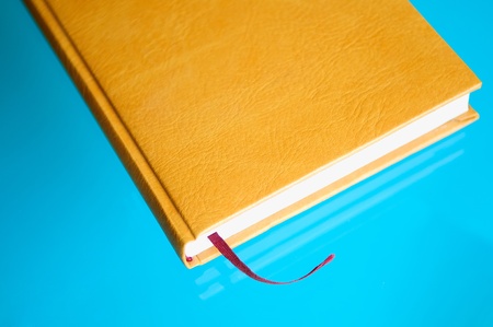 brown leather notebook with a red tab on the blue background.の写真素材