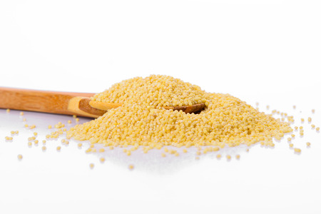 Millet in a wooden spoon isolated on a white background