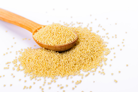 Millet in a wooden spoon isolated on a white backgroundの写真素材