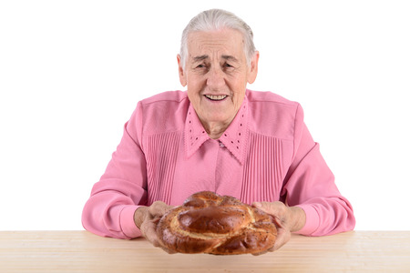 old woman sitting near table and holding a bread. portrait isolated on white backgroundの写真素材