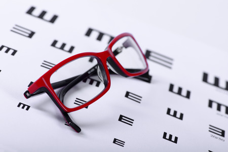 Reading red eyeglasses and eye chart close-up on a light backgroundの写真素材