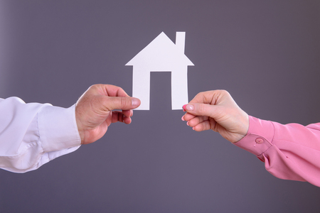 Male and female hands holding a paper houseの写真素材