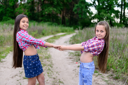 Two cute little sisters having fun together in park on a sunny summer dayの写真素材