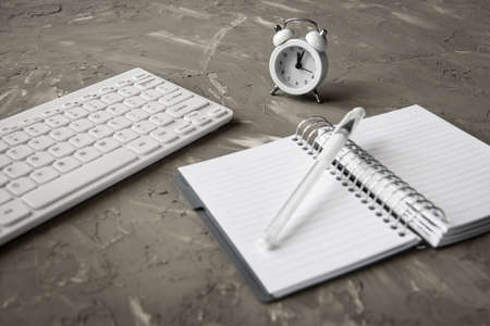 workplace office accessories on a dark table - a keyboard and alarm clockの写真素材
