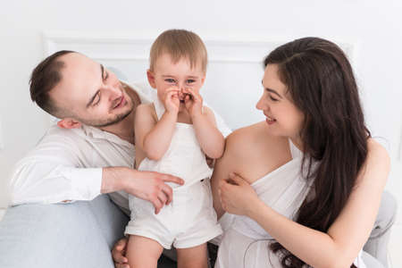 happy family in the living room married couple with a small child and pregnant woman