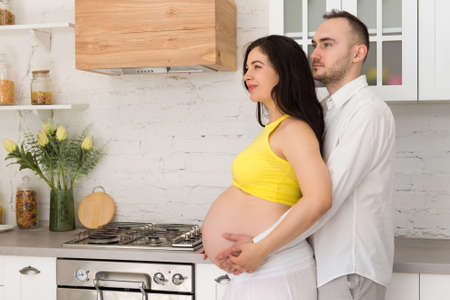 happy family in home kitchen married couple with pregnant womanの写真素材