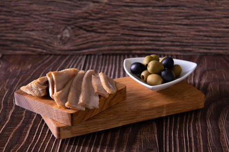 tuna slices with olives on cutting board on a wooden background closeupの写真素材