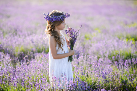 Beautiful girl in a field of lavender on sunset. Girl in amazing dress walk on the lavender field.の写真素材