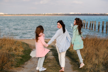 Happy family, mom and daughters at dawn outdoorの写真素材