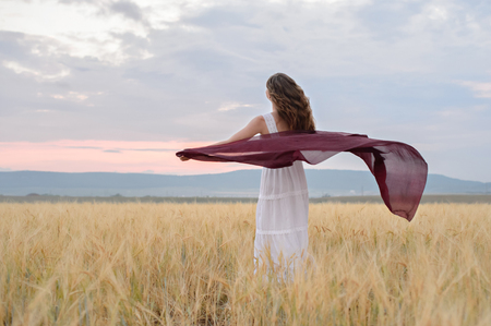A woman in amazing clothes walking through the field of rye.の写真素材