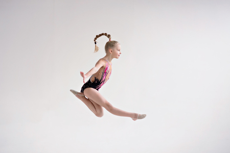 Little girl gymnast, performs various gymnastic and fitness exercises. The concept of childhood and sport, a healthy lifestyle.の写真素材