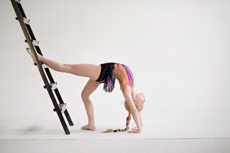 Little girl gymnast, performs various gymnastic and fitness exercises. The concept of childhood and sport, a healthy lifestyle.の写真素材
