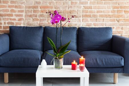 Living room table with orchid flowerpot, candles and air refresher sticks in modern interior design.の写真素材