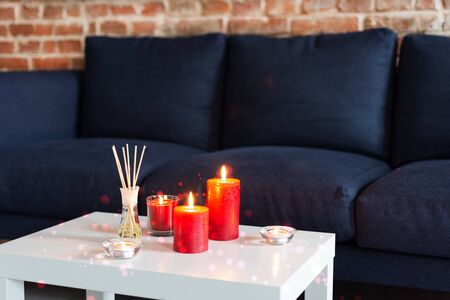 Room air refresher sticks and red burning candles on table on home modern interior.の写真素材