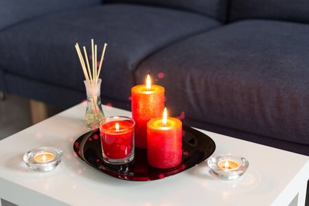Room air refresher sticks and red burning candles on table on home modern interior.の写真素材