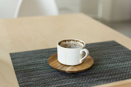 Empty white coffee cup on table napkin. Cup after drinking coffee with wooden saucer top view.の写真素材