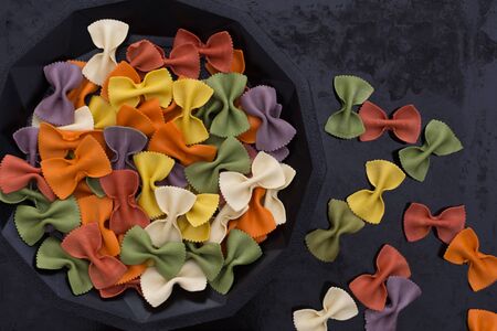 Italian raw multicolored farfalle pasta close-up on black background. Colorful pasta in bow tie shape. Italian cuisine concept.の写真素材