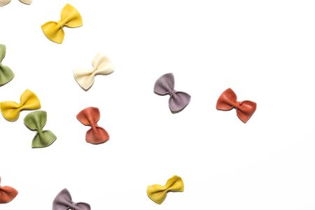 Italian raw multicolored farfalle pasta on white background with copy space. Colorful pasta in bow tie shape. Italian cuisine concept. Mockup for design.の写真素材