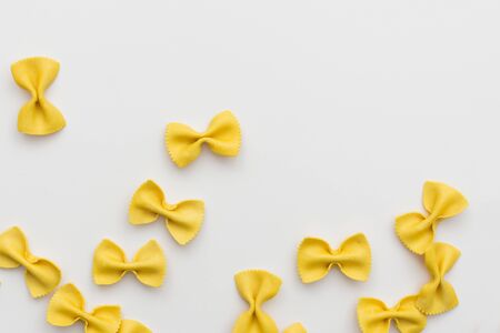 Italian raw multicolored farfalle pasta on white background with copy space. Colorful pasta in bow tie shape. Italian cuisine concept. Mockup for design.の写真素材