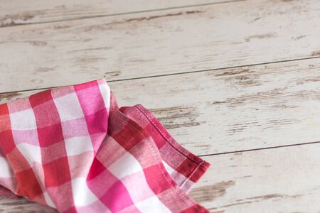 Red checkered napkin on wooden background Background with napkin, template for design.