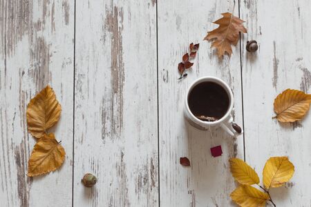 Cup of tea, autumn leaves on wooden table top view. Cozy autumn background. Copy space.の写真素材