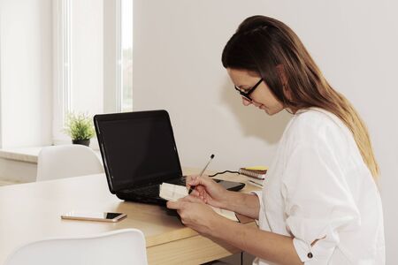 Young business woman working in the office on laptop. Business brunette woman making notes.の写真素材