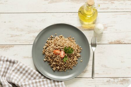 A plate with buckwheat porridge with tomato and parsley. Olive oil and sour cream for dressing.の写真素材