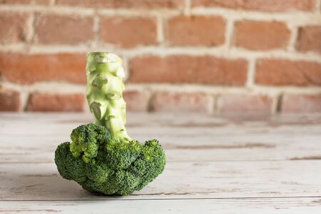 Bunch of fresh green broccoli on wooden background against brick wall closeup. Healthy eating concept.の写真素材