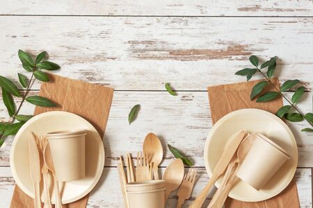 Eco friendly disposable dishes made of bamboo wood and paper on white wooden background. Zero waste, eco friendly, plastic free background.の写真素材