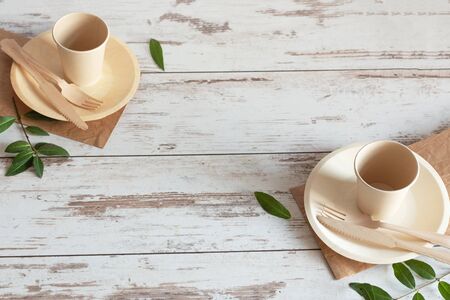 Eco friendly disposable dishes made of bamboo wood and paper on white wooden background. Zero waste, eco friendly, plastic free background.の写真素材