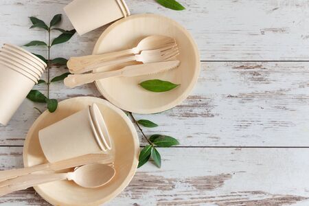 Eco friendly disposable dishes made of bamboo wood and paper on white wooden background. Zero waste, eco friendly, plastic free background.の写真素材