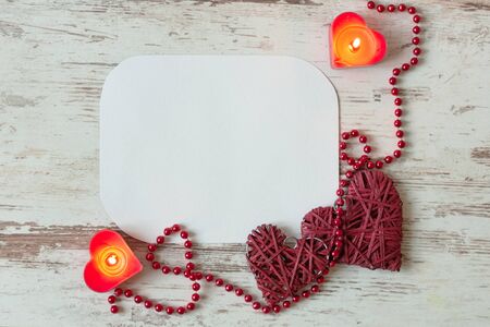 Hearts with red bead chain and candles on wooden background. St. Valentines Day or Wedding card concept with copy space .の写真素材