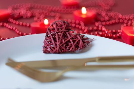 Serving table with fork, knife, napkin and heart decoration for Valentine's . Dinner table in red colors on Valentines day. Top view.の写真素材