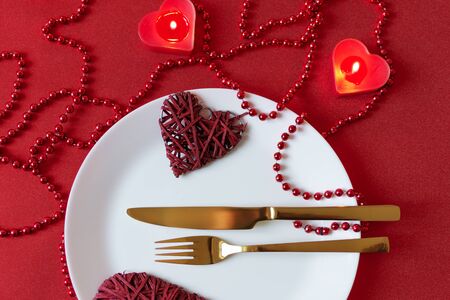 Serving table with fork, knife, napkin and heart decoration for Valentine's . Dinner table in red colors on Valentines day. Top view.の写真素材