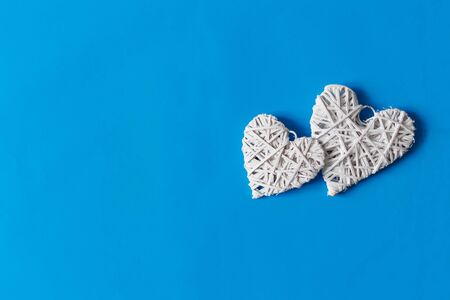 Two white wooden hearts on blue background. Valentine's Day postcard. Copy space. Top view. Flat lay.の写真素材