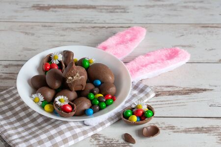 Chocolate Easter eggs and bunny on a plate on wooden background. Easter concept.